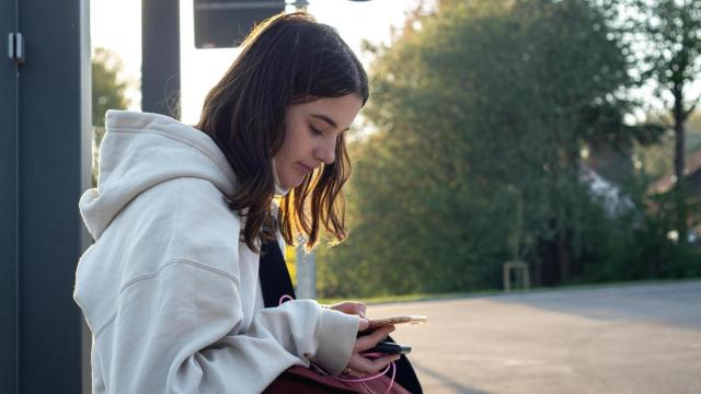 Joven esperando en una parada de autobús.