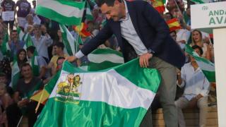El presidente de la Junta, Juanma Moreno, coge una bandera andaluza durante el primer acto de campaña del pasado 19 de junio.