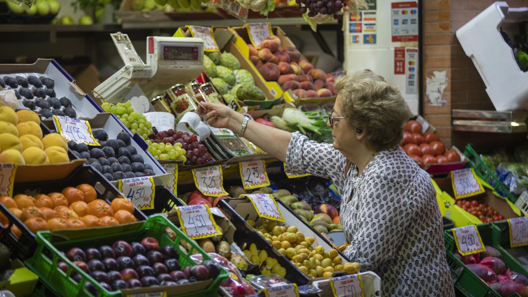 Una mujer compra en uno de los puestos del mercado de abastos de Triana.