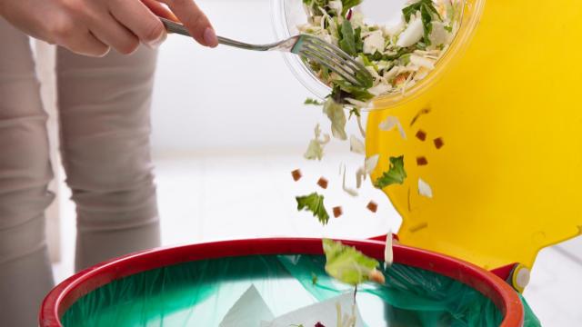 Una mujer tirando comida a la  basura