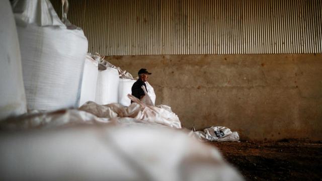 Un agricultor frente a unas bolsas de fertilizantes