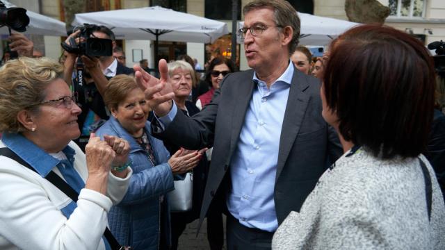 El presidente del PP, Alberto Núñez Feijóo, saluda a varias vecinas durante un paseo por el centro de Vitoria, este viernes.