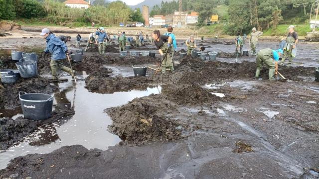 Mariscadores retirando la capa de sedimentos en la playa de Os Raposiños
