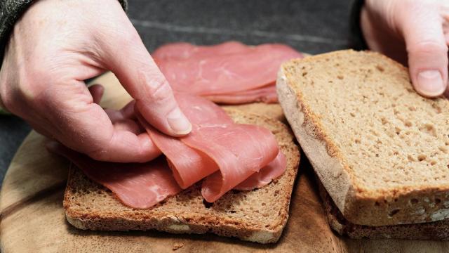 Una persona hace un bocadillo de jamón.