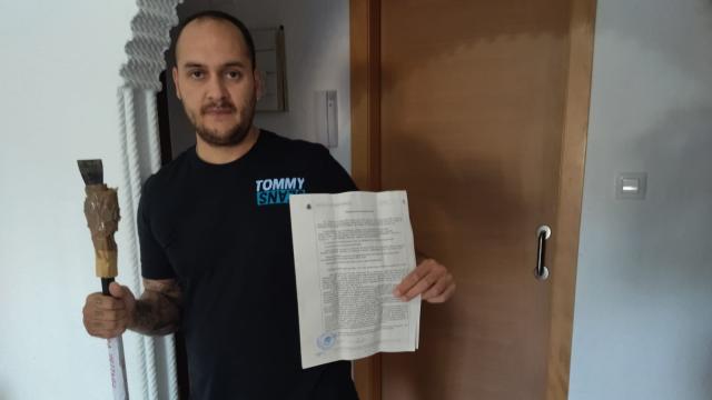Pedro, en su domicilio de Cartagena, mostrando la pata de cabra y la denuncia que su familia presentó en marzo ante la Guardia Civil por la ocupación de la casa que habían heredado.