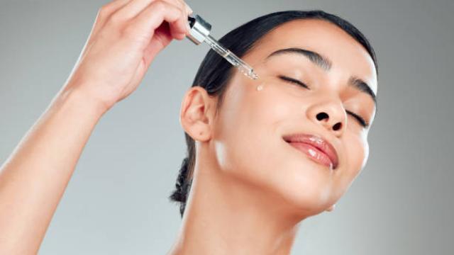 Mujer aplicándose sérum. Istock