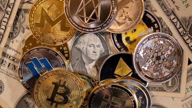 Representación física de varias criptomonedas sobre billetes de dólar.