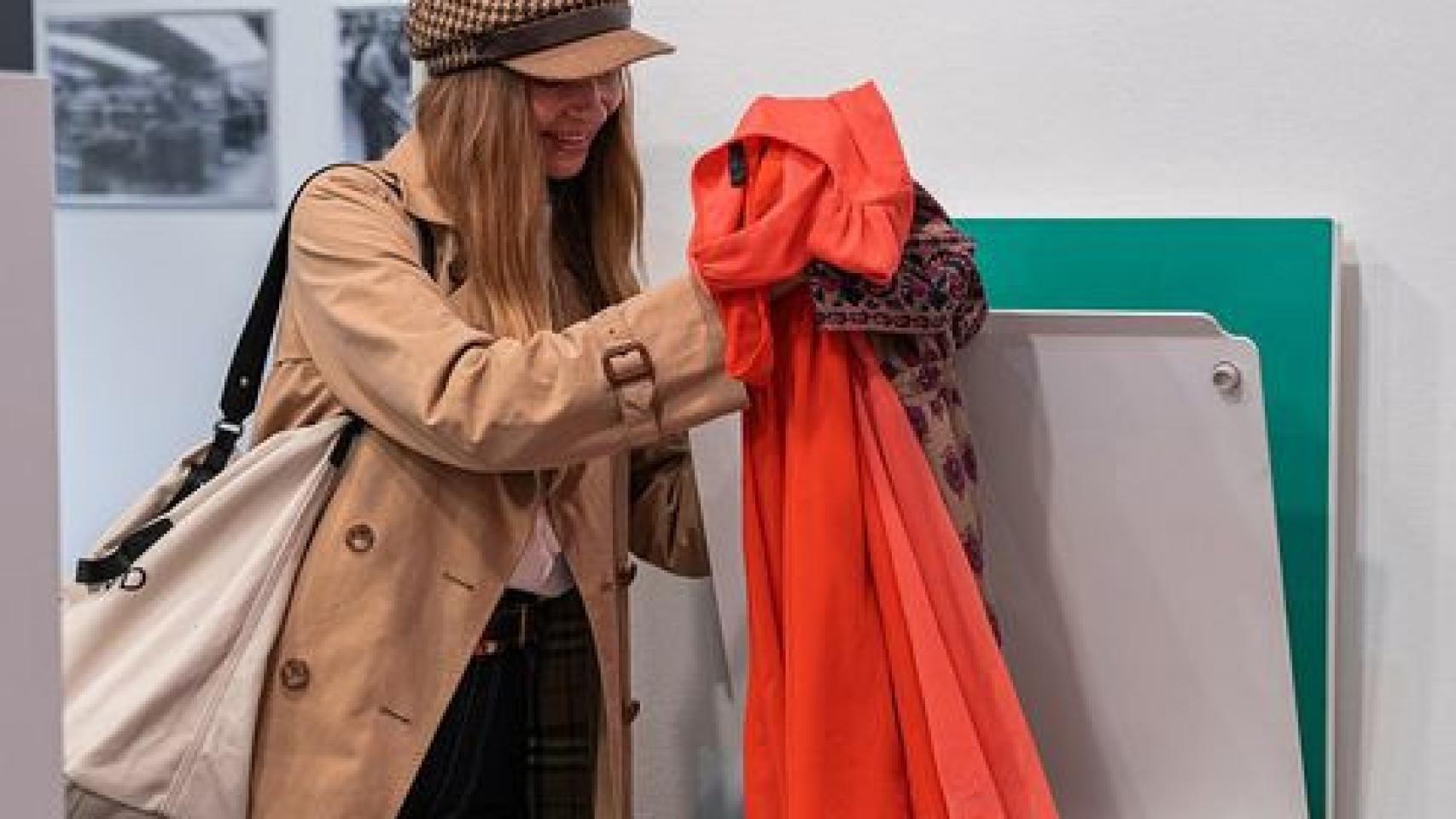 Una mujer deposita ropa en un contenedor para esta iniciativa.