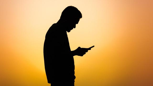 Silueta de un hombre utilizando su teléfono móvil.