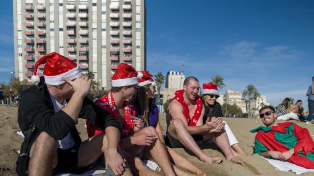 Unos turistas con gorros de Navidad disfrutan de las altas temperaturas en la playa de la Barceloneta, a 25 de diciembre de 2022, en Barcelona.