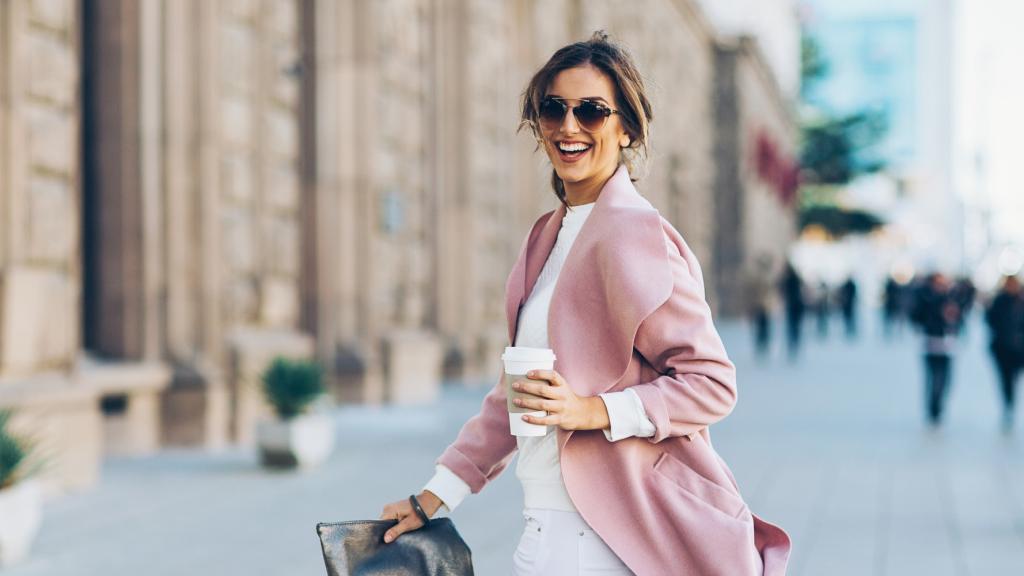 Una mujer camina sola feliz por la calle.