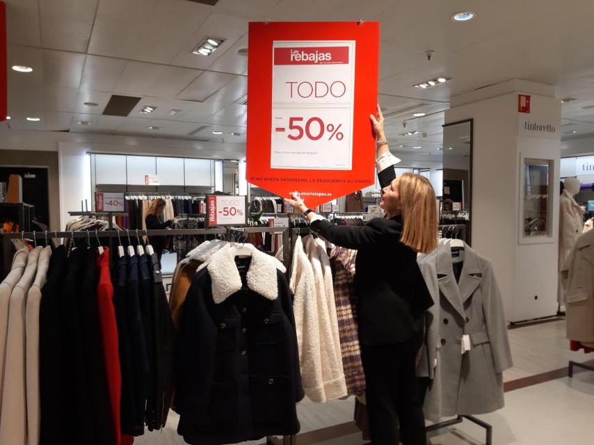 Una trabajadora coloca los carteles de rebajas en El Corte Inglés de Valladolid.