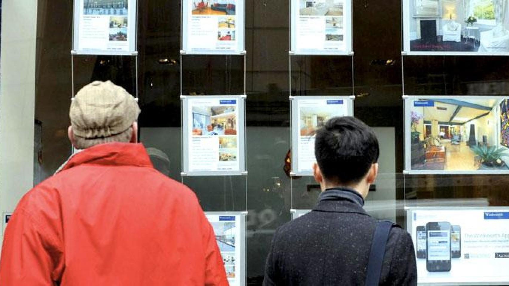 Dos clientes miran viviendas en una inmobiliaria.