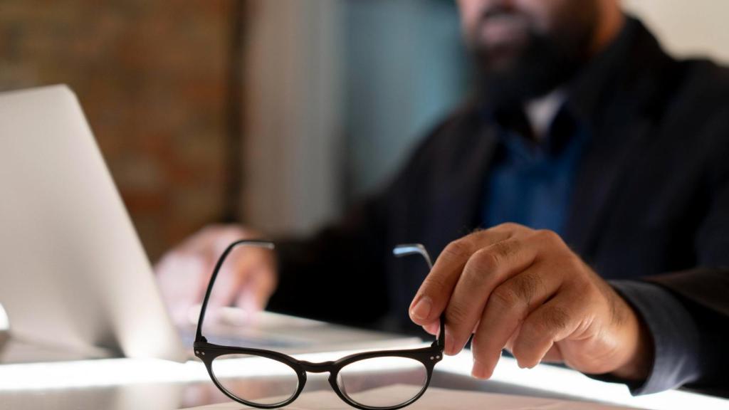Un trabajador sujetando unas gafas en la mano.