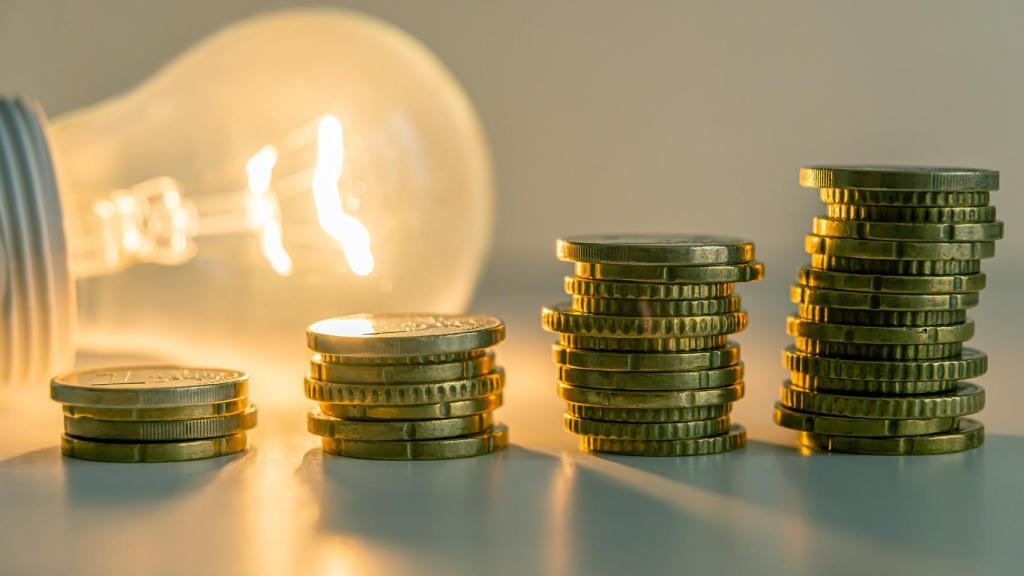 Una bombilla junto a varias monedas para ilustrar el precio de la luz.
