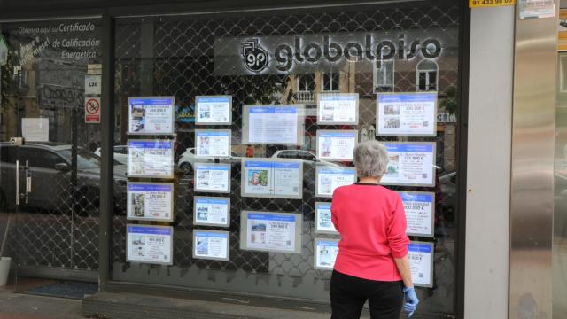 Una mujer mira la oferta de pisos de una agencia inmobiliaria.