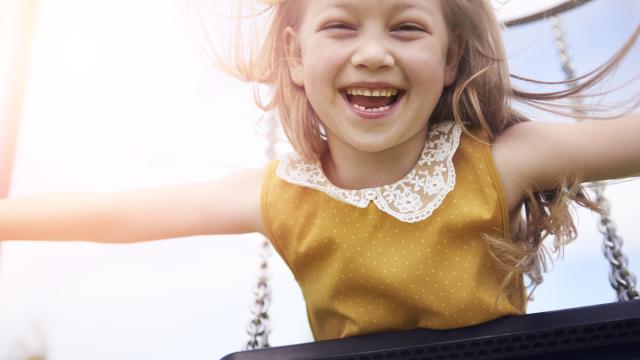 Una niña jugando feliz en un columpio.