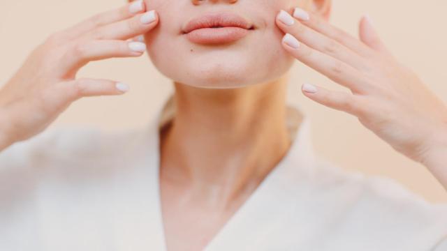 Una mujer, tocando su rostro.