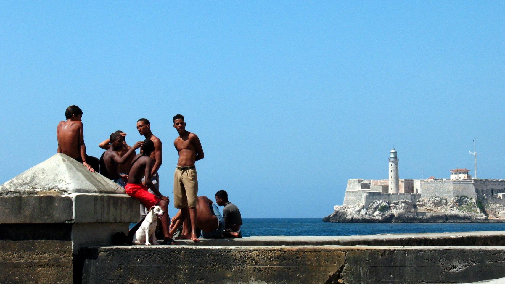 Habaneros disfrutando del sol de Cuba en el malecón de La Habana con el castillo del Morro de fondo. Foto: Elemaki