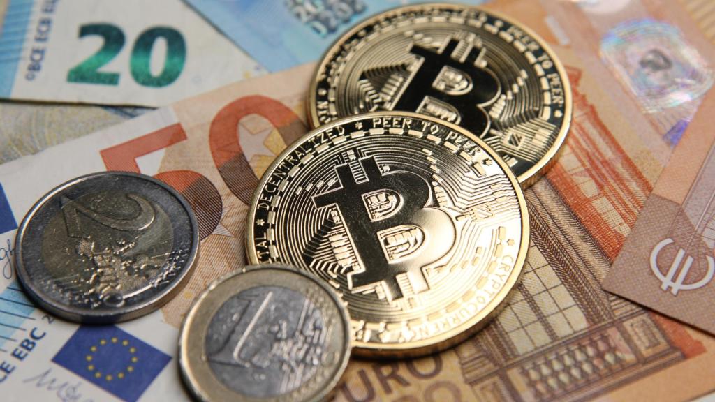 Representación física de unos bitcoin sobre billetes de euro.