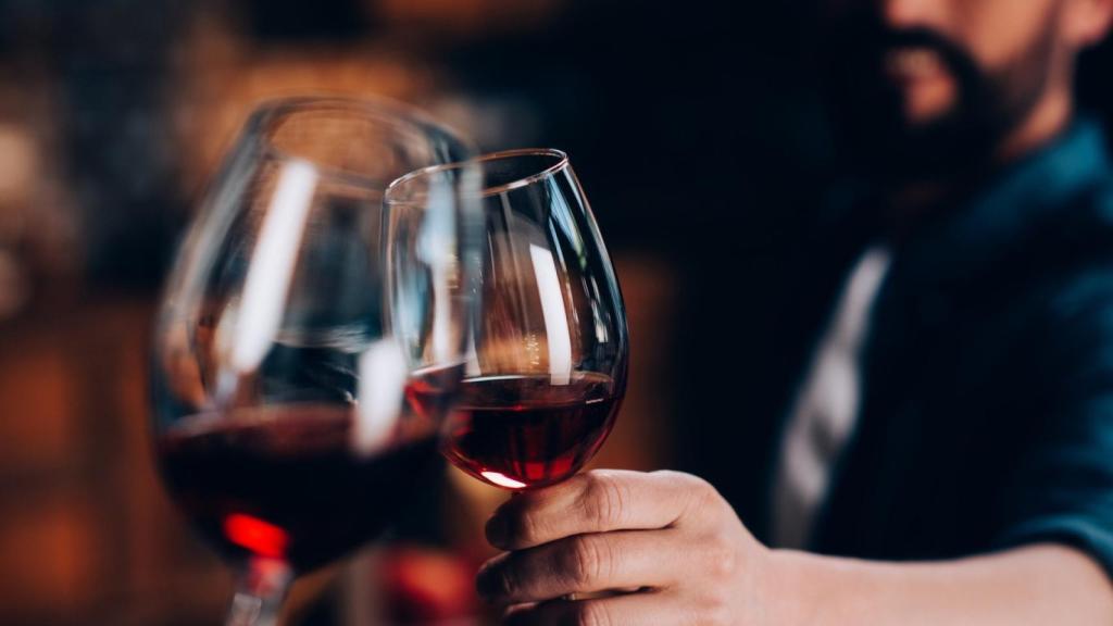Una pareja brindando con una copa de vino.