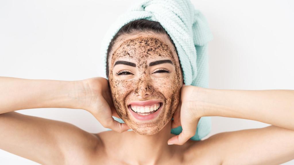 Joven mujer sonriente aplicando mascarilla de exfoliación