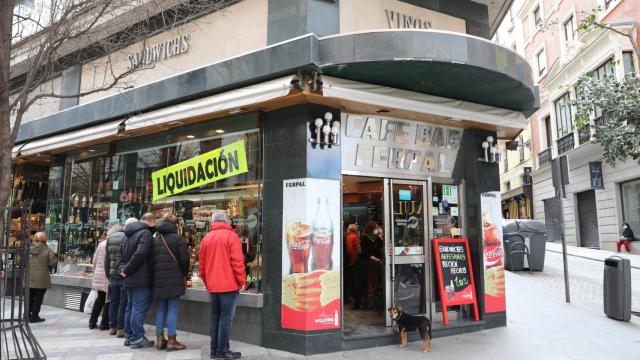 Varias personas frente al escaparate de una histórica cafetería que cerró en Madrid.