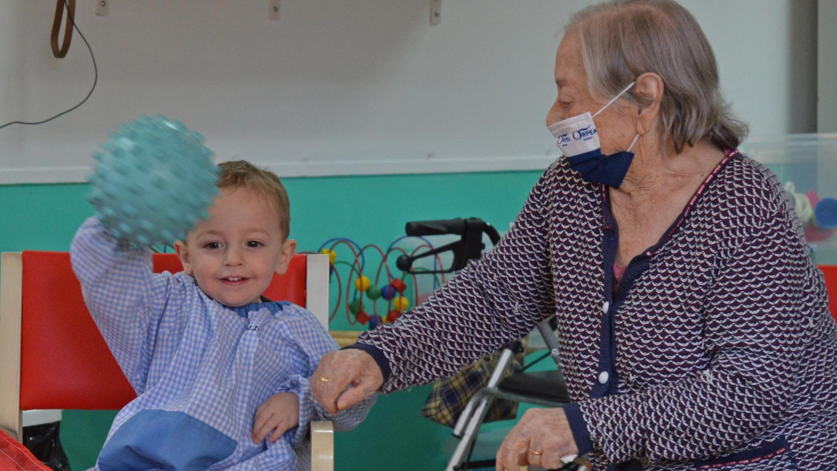 El pequeño Oliver y la anciana Calixta juegan con una pelota en una de las actividades propuestas en la Residencia Orpea de Meco.