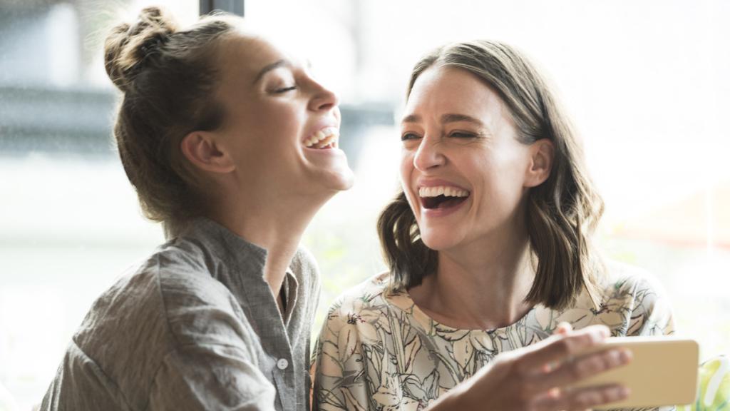 Dos mujeres, sonriendo.