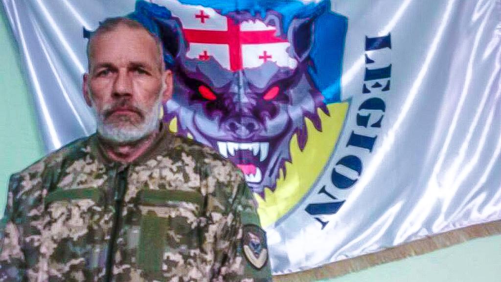 John Harding posa junto a una bandera de la Legión Nacional de Georgia.