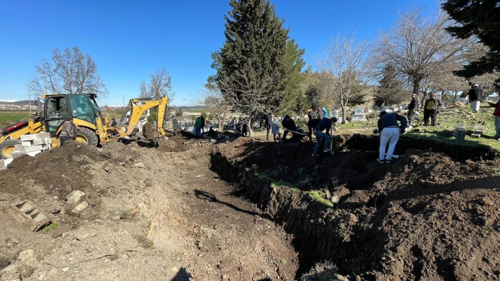 Vecinos con palas y la ayuda de una excavadora cavan una fosa común en el cementerio a la entrada de Nurdagi.