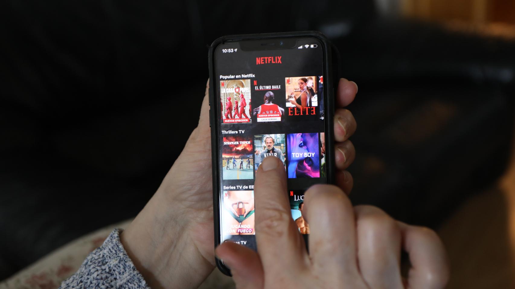 Una persona utilizando la aplicación de Netfix en su teléfono móvil.