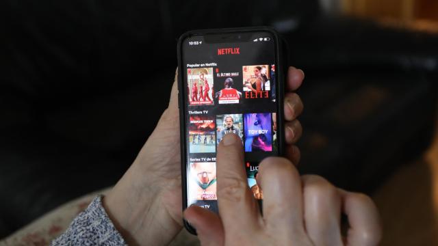 Una persona utilizando la aplicación de Netfix en su teléfono móvil.