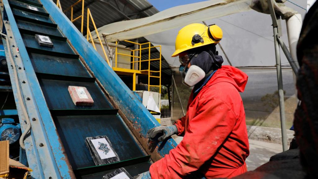 Un operario coloca bloques de cocaína en una cinta para su tratamiento.