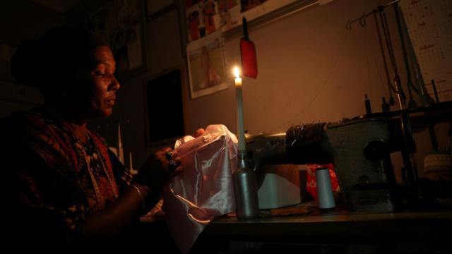 La modista Faieza Caswell cose a la luz de las velas en su lugar de trabajo.