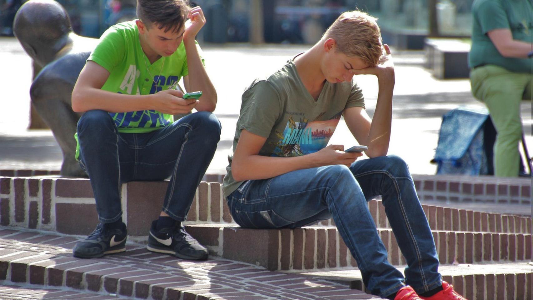Dos adolescentes usan sus teléfonos móviles.