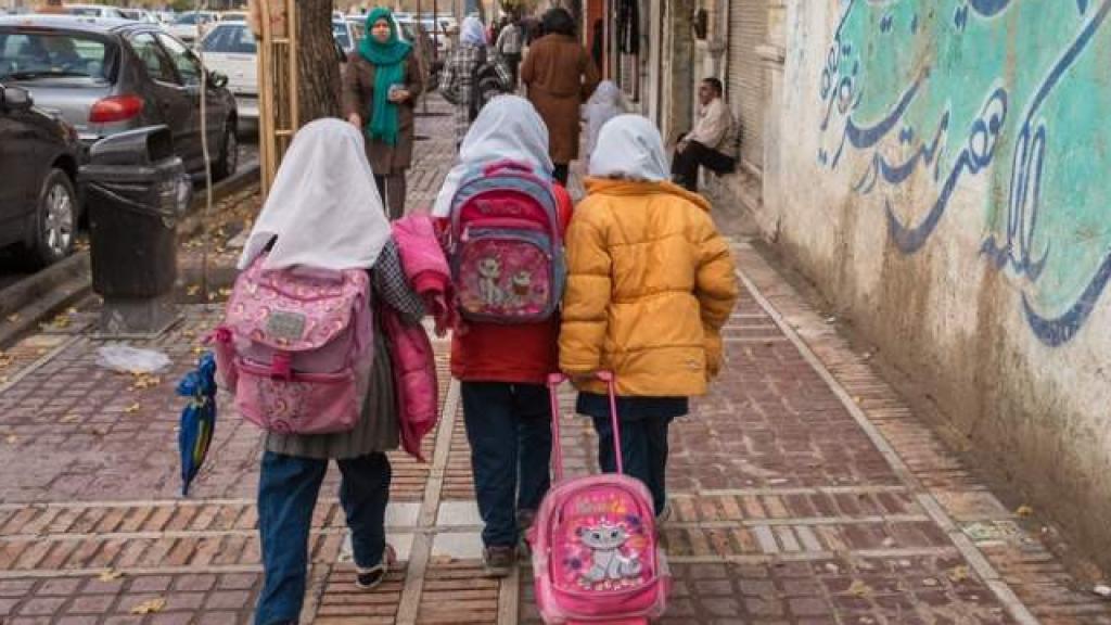 Tres niñas iraníes pasean con sus mochilas por una calle de Teherán.