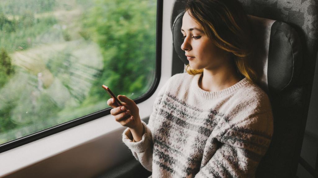 Imagen de archivo de una chica con su móvil en el tren.
