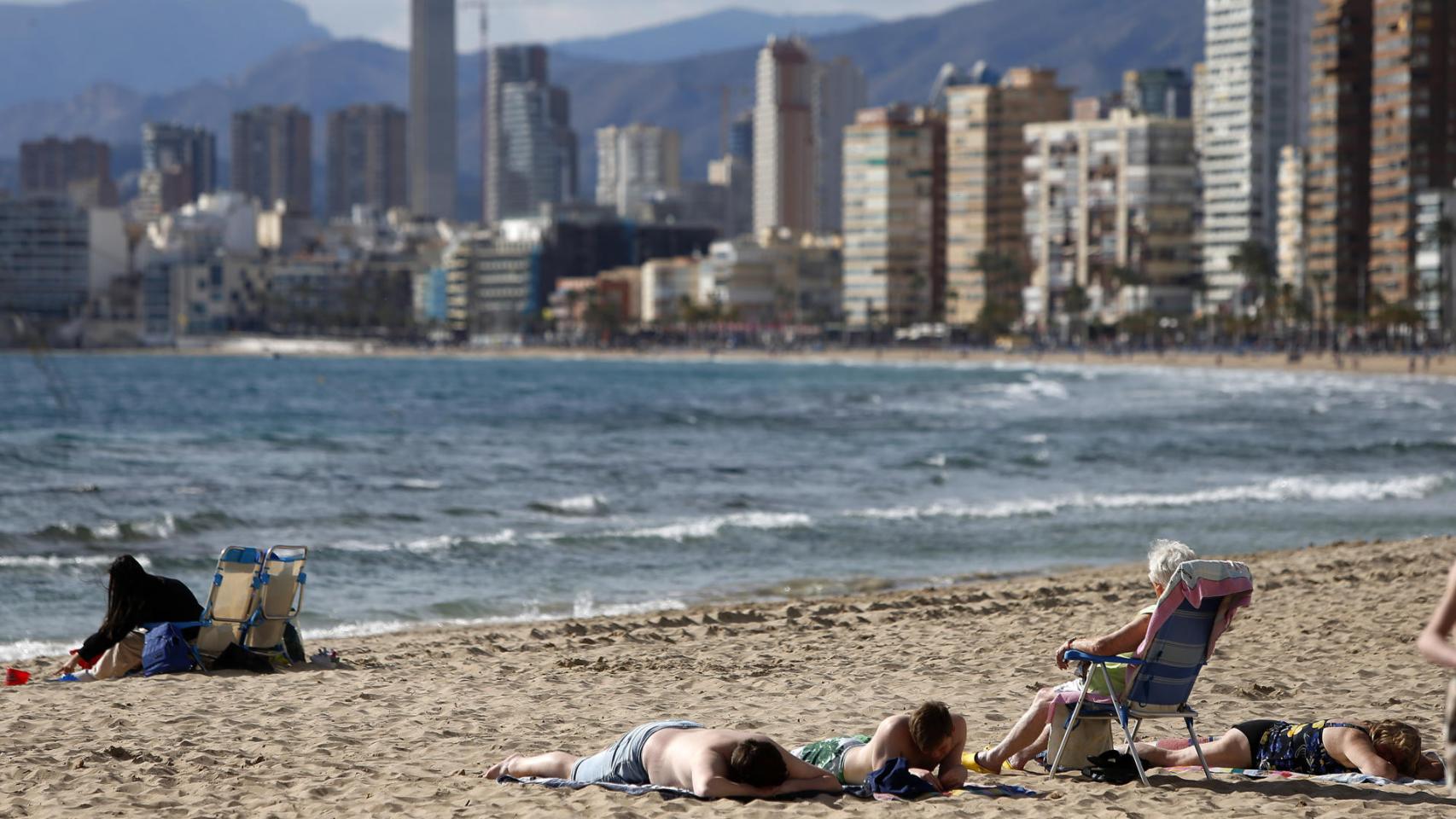 Varios turistas en una playa de Benidorm con el 'skyline' de fondo, este mes de febrero.