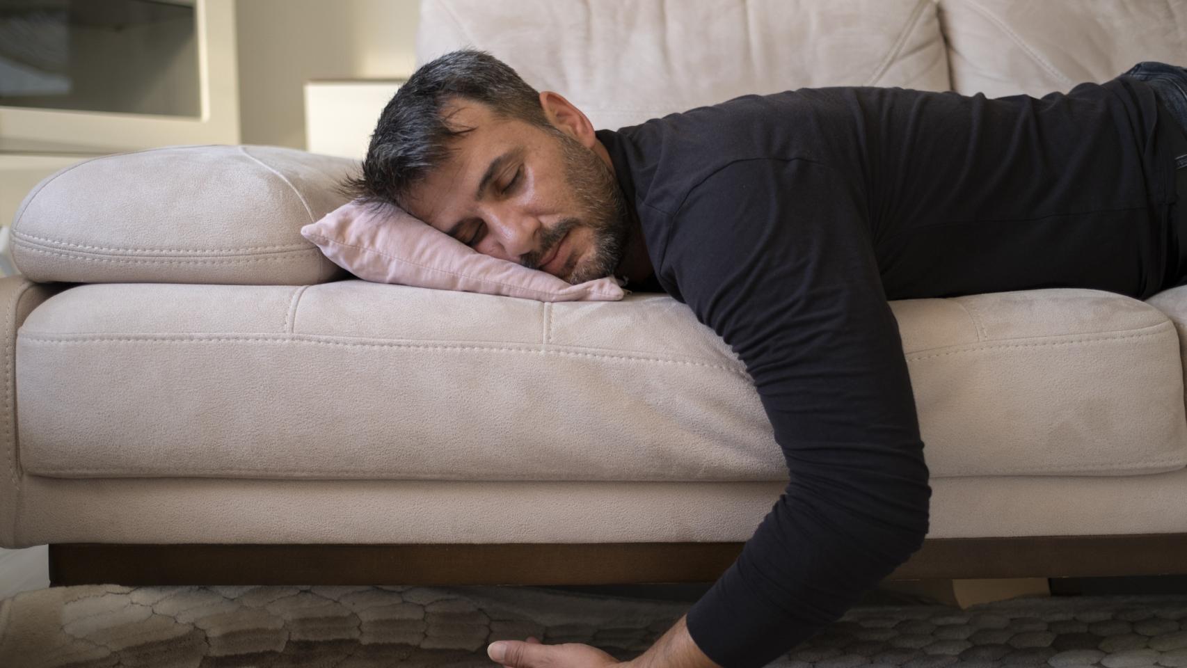 Imagen de archivo de una persona de mediana edad durmiendo en el sofá.