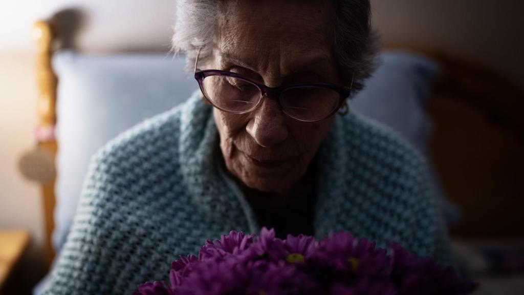 La tatarabuela mirando un ramo de flores.