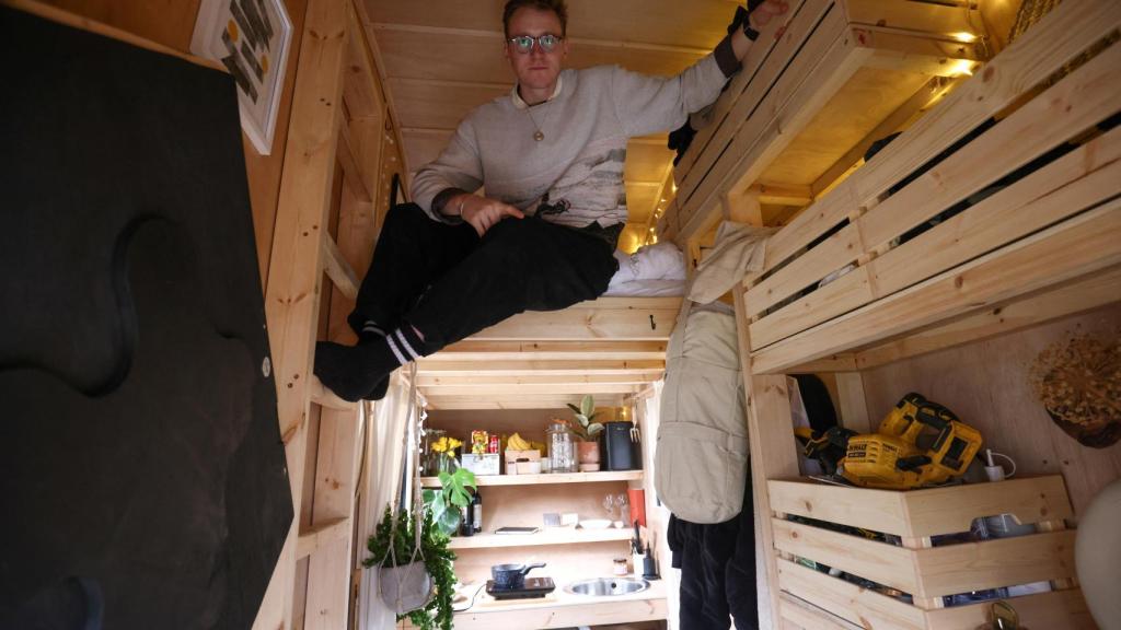 El artista Harrison Marshall posa en el interior del contenedor que ha convertido en vivienda, en la que pretende vivir durante un año.