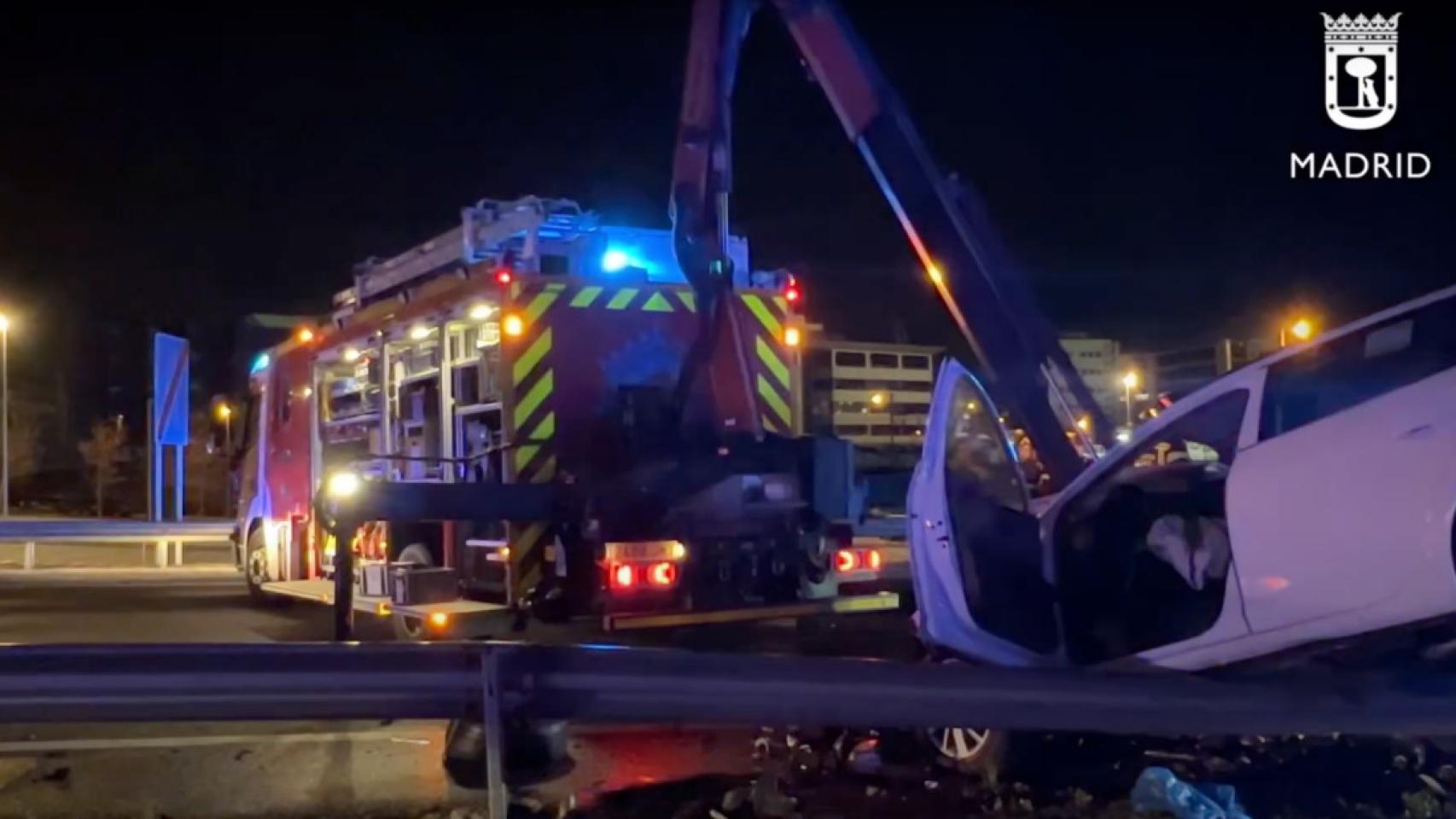 Los bomberos bajan de un guardarraíl el taxi embestido por el kamikaze de la M-11 el pasado domingo.