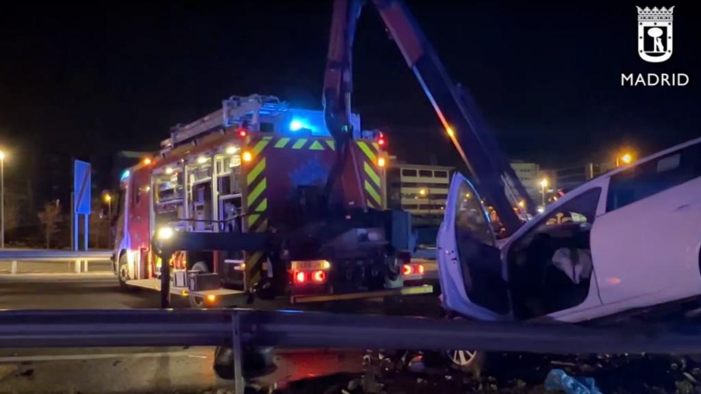 Los bomberos bajan de un guardarraíl el taxi embestido por el kamikaze de la M-11 el pasado domingo.