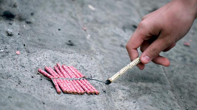 Un fallero enciende unos petardos.