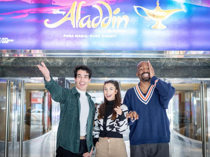 Roc Bernadí (izq.), Jana Gómez y David Comrie viendo pasar un autobús con la promoción de Aladdín en la entrada del Teatro Coliseum.