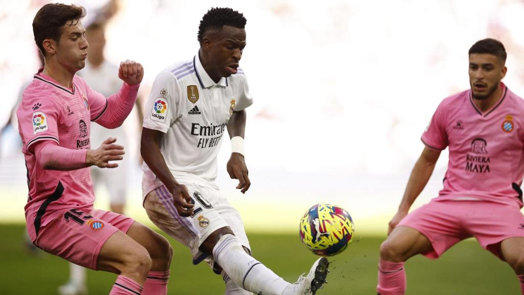 Vinicius, en primer plano intentando regatear a dos futbolistas.