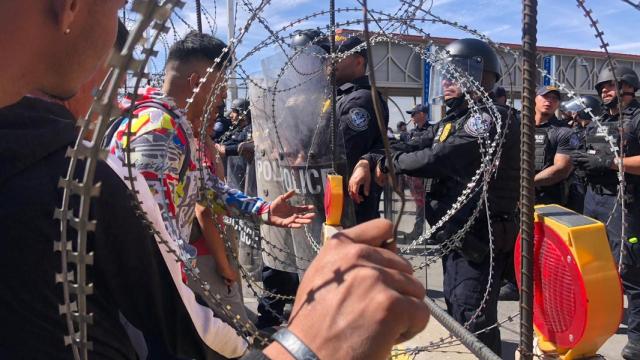 Los migrantes exigen a la policía entrar en EEUU a través del alambre de espino.