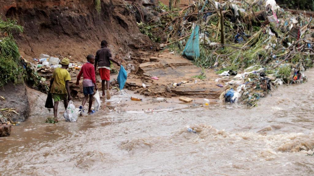 Unos niños llevan plástico mientras buscan artículos para rescatar del río Nasolo en el municipio de Ndirande en Blantyre, Malawi, 15 de marzo de 2023.