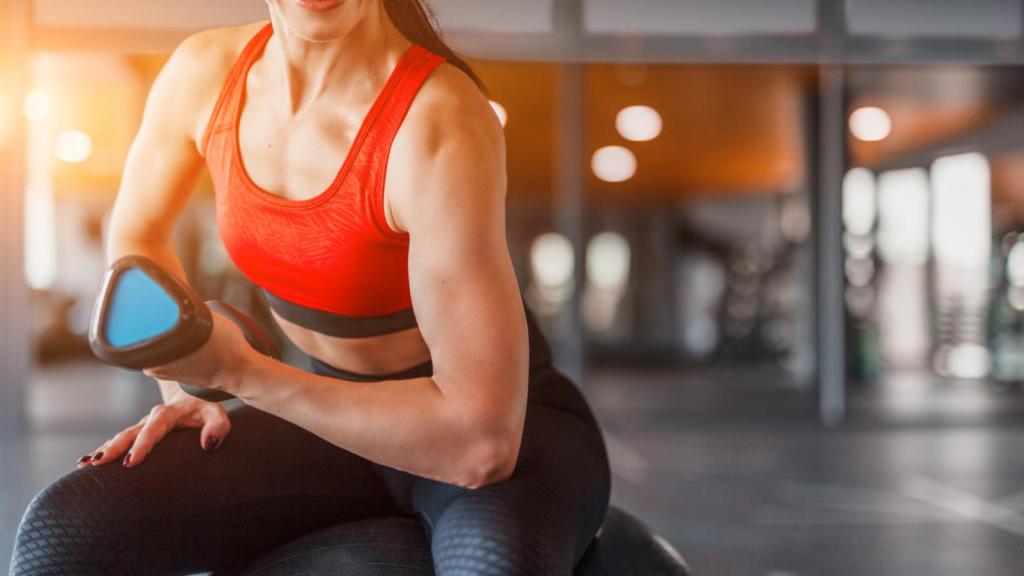 Una mujer realizando curl de bíceps en el gimnasio.